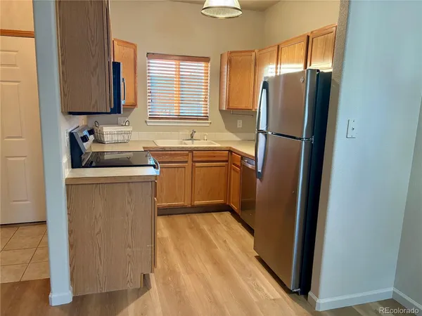 a kitchen with stainless steel appliances granite countertop a refrigerator a sink a stove a washer dryer and a window