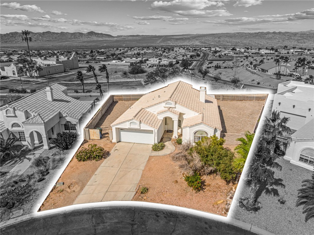 2853 Winchester Road Bullhead City, AZ 86442 - Photo 2 of 40 The property features a concrete driveway leading to a two-car garage, a well-maintained tile roof, and a fully fenced backyard area
