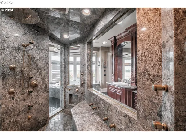 a bathroom with a granite countertop sink a large mirror and a bathtub