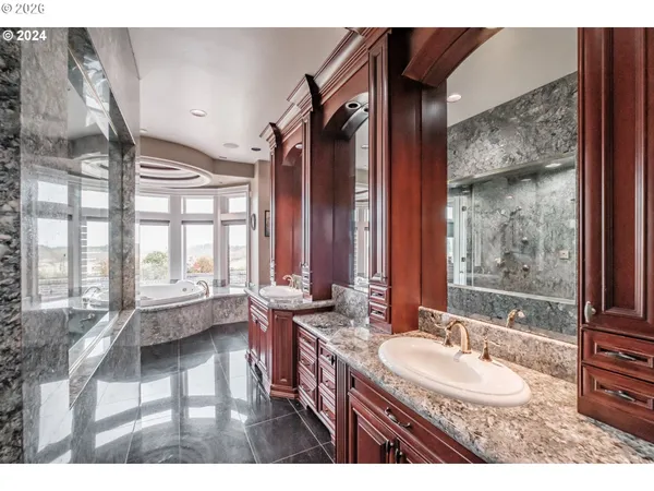 a bathroom with a granite countertop sink a mirror and a bathtub