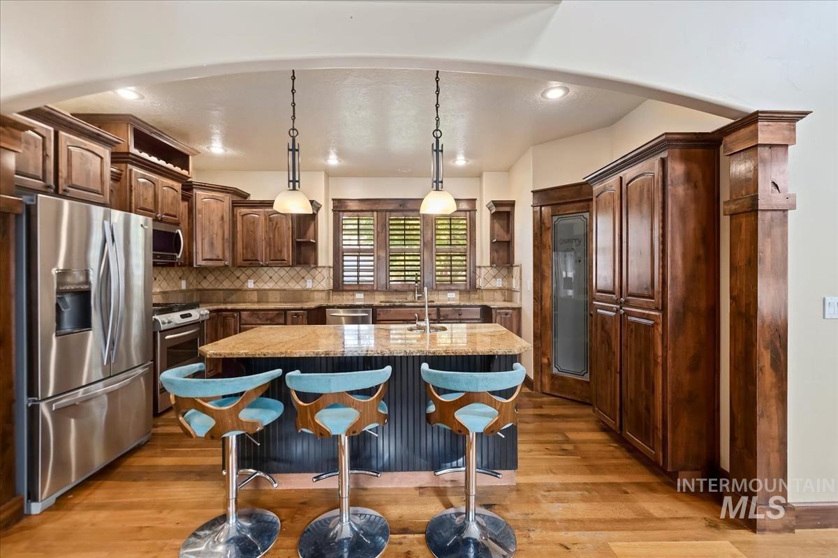 2543 West Divide Creek Street Meridian, ID 83646 - Photo 11 of 49 Kitchen with pendant lighting, open shelves, appliances with stainless steel finishes, a breakfast bar area, and an island with sink