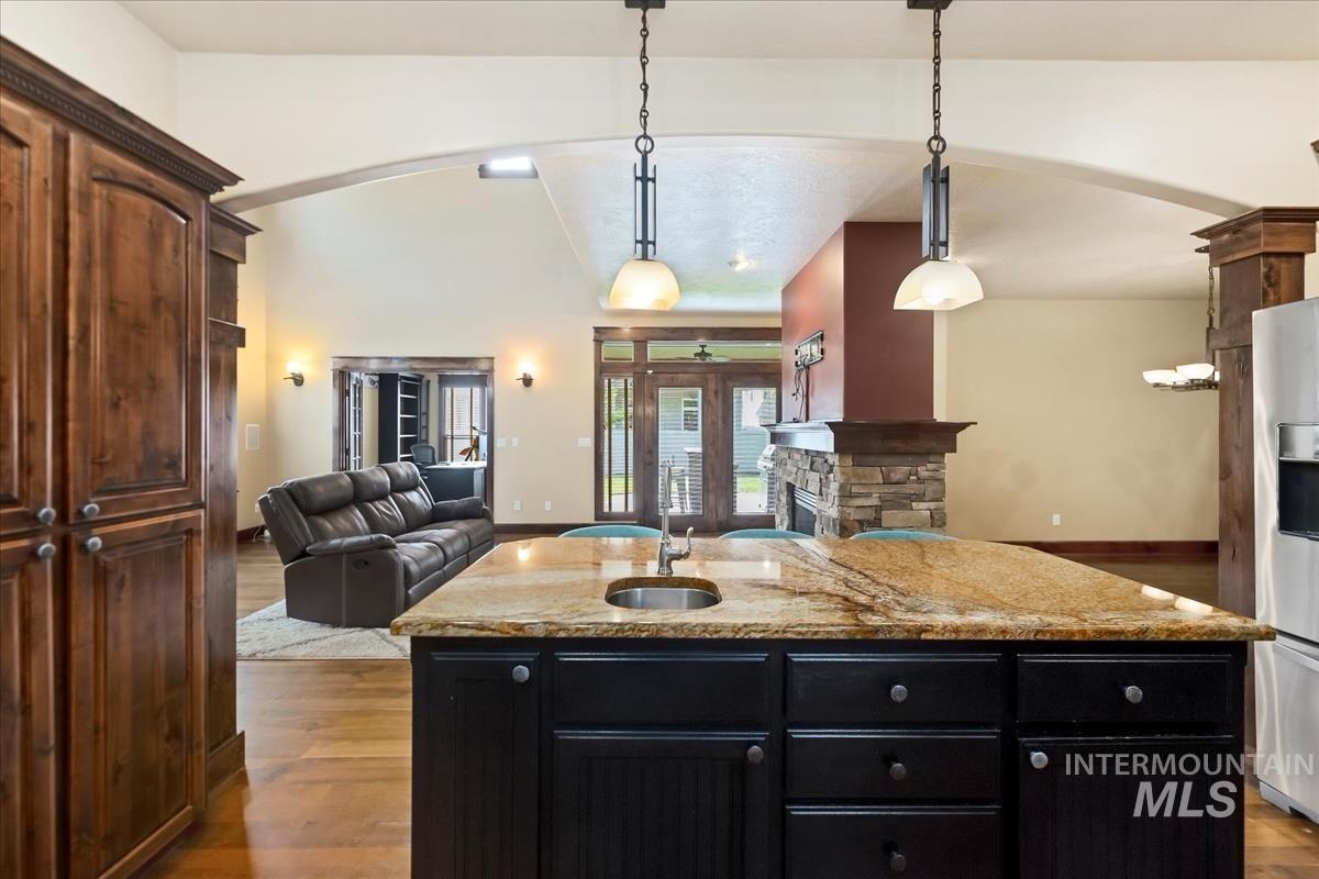 2543 West Divide Creek Street Meridian, ID 83646 - Photo 49 of 49 Kitchen with dark cabinetry, open floor plan, a center island with sink, light stone counters, and arched walkways