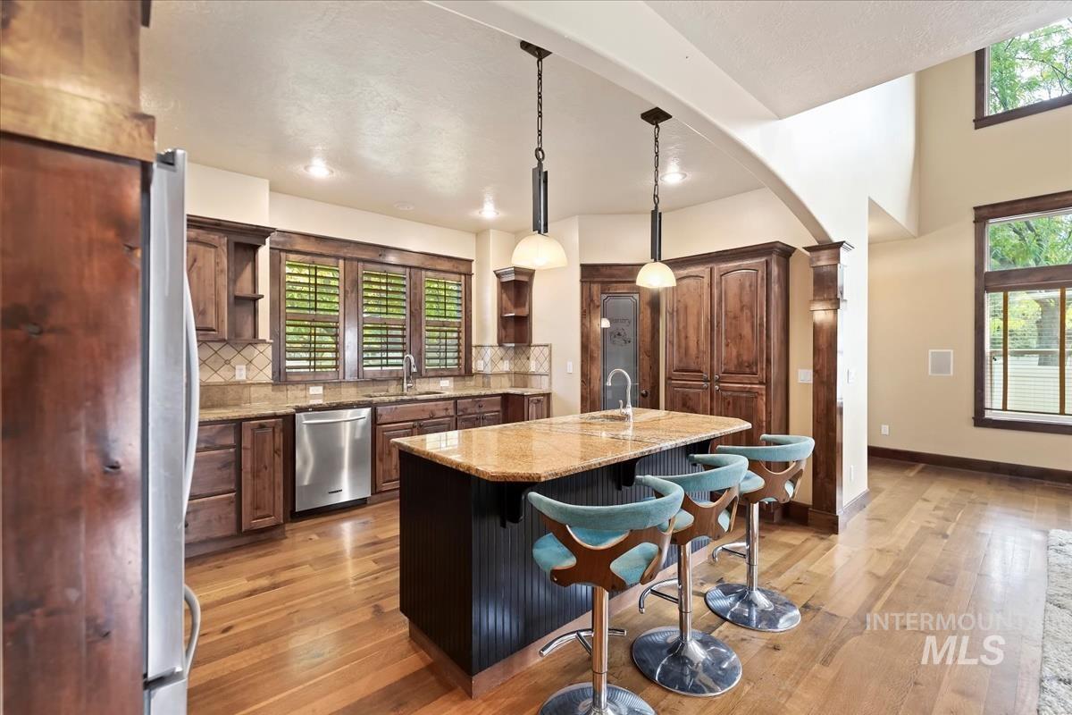 2543 West Divide Creek Street Meridian, ID 83646 - Photo 15 of 49 Kitchen featuring open shelves, a kitchen bar, a center island with sink, decorative light fixtures, and healthy amount of natural light