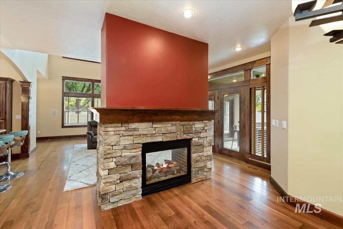 2543 West Divide Creek Street Meridian, ID 83646 - Photo 16 of 49 Unfurnished living room featuring wood finished floors, plenty of natural light, and a stone fireplace