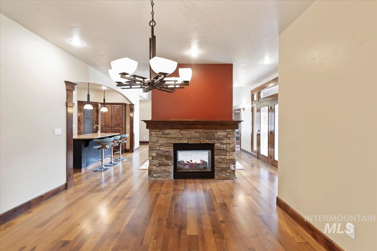 2543 West Divide Creek Street Meridian, ID 83646 - Photo 17 of 49 Unfurnished living room with light wood-type flooring, a fireplace, arched walkways, and a chandelier