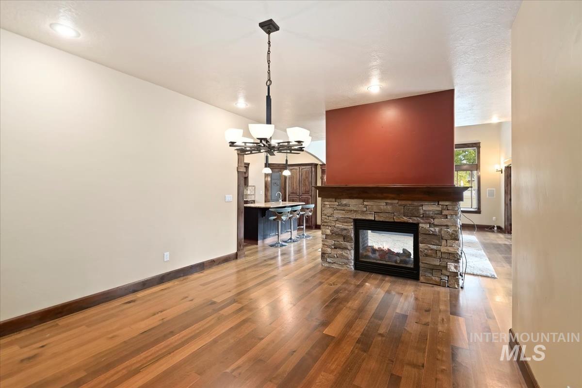 2543 West Divide Creek Street Meridian, ID 83646 - Photo 18 of 49 Unfurnished living room featuring a stone fireplace, wood finished floors, and a chandelier