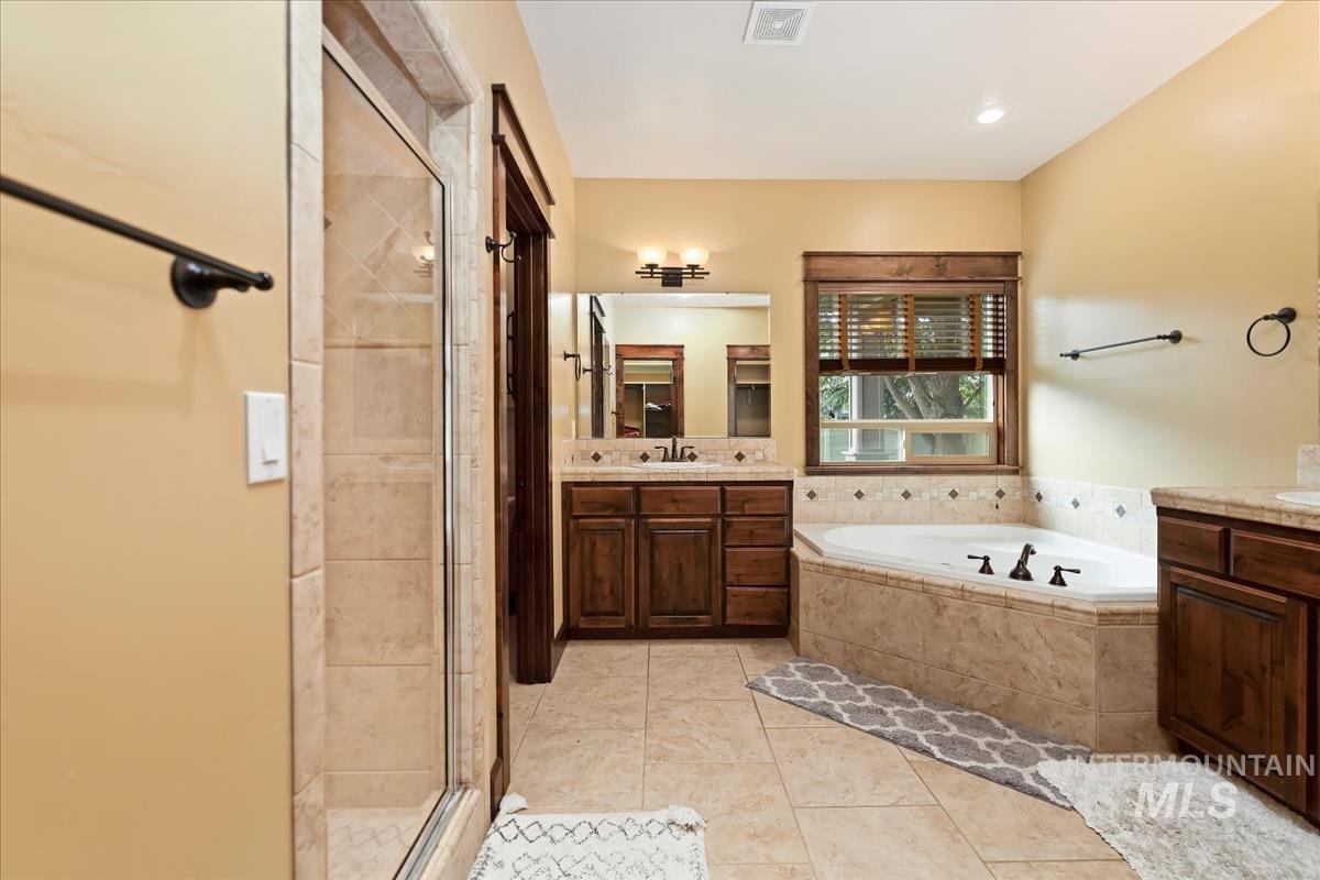 2543 West Divide Creek Street Meridian, ID 83646 - Photo 23 of 49 Full bathroom featuring a shower stall, two vanities, a garden tub, and light tile patterned flooring