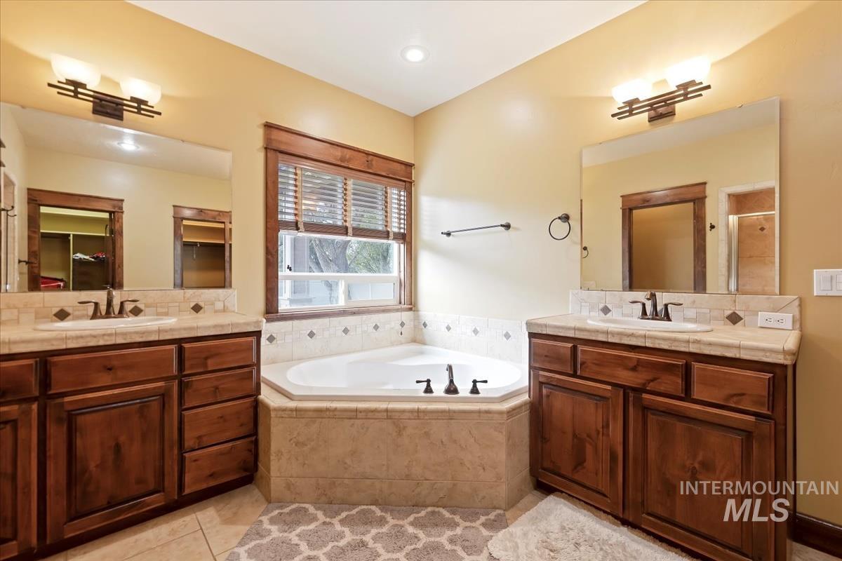 2543 West Divide Creek Street Meridian, ID 83646 - Photo 24 of 49 Full bathroom featuring light tile patterned floors, two vanities, a bath, a stall shower, and recessed lighting