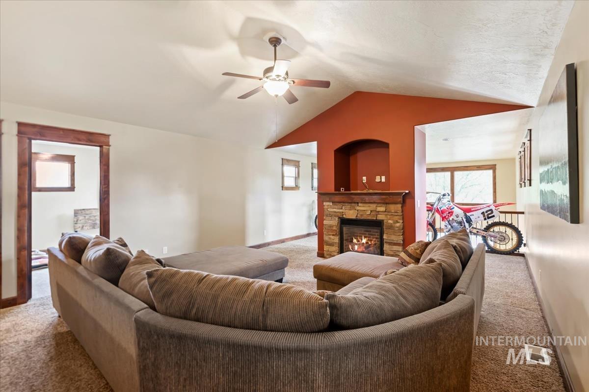 2543 West Divide Creek Street Meridian, ID 83646 - Photo 31 of 49 Living area with carpet flooring, vaulted ceiling, a stone fireplace, and ceiling fan