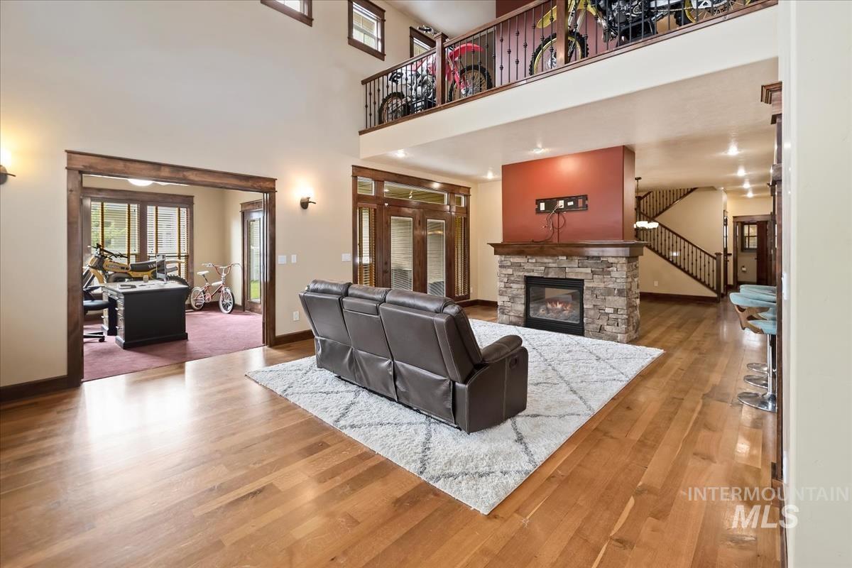 2543 West Divide Creek Street Meridian, ID 83646 - Photo 4 of 49 Living area featuring a stone fireplace, wood finished floors, a high ceiling, and stairs