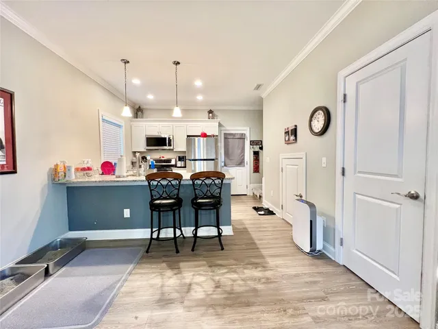 a living room with stainless steel appliances furniture a rug and a kitchen view