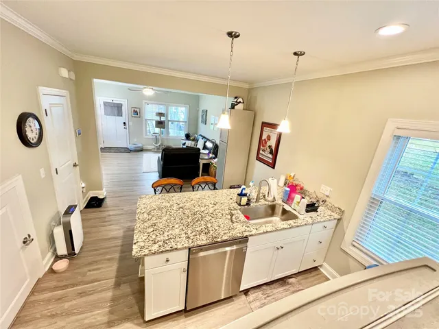 a living room with stainless steel appliances kitchen island granite countertop furniture a rug and a wooden floor