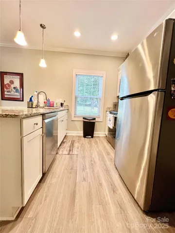 a kitchen with stainless steel appliances granite countertop a refrigerator a sink dishwasher a stove and white countertops with wooden floor