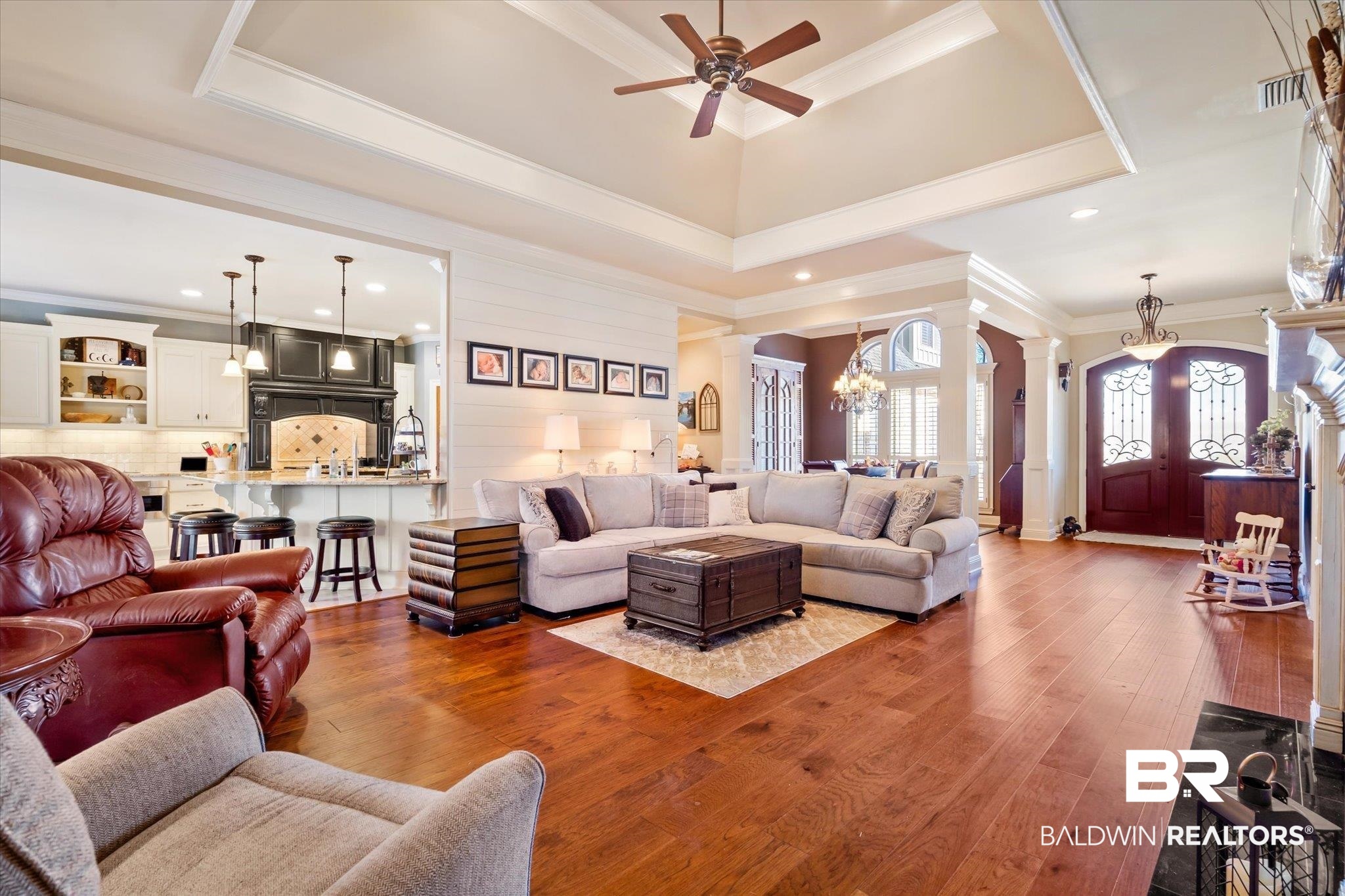 5683 Spring Landing Drive Theodore, AL 36582 - Photo 6 of 49 Living room featuring hardwood / wood-style floors, ceiling fan with notable chandelier, ornate columns, a raised ceiling, and ornamental molding