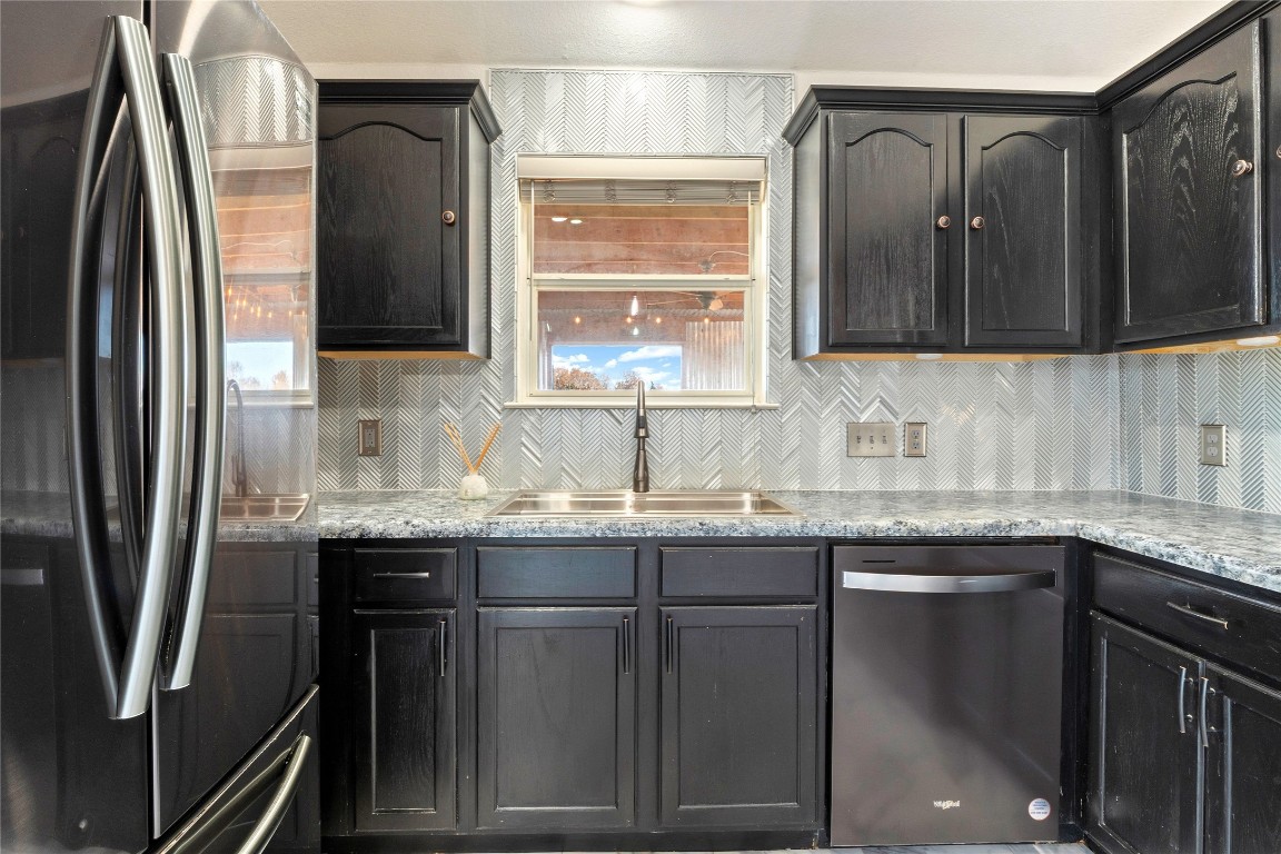 167 Hay Meadow Road Cedar Creek, TX 78612 - Photo 13 of 39 Kitchen with appliances with stainless steel finishes, tasteful backsplash, light stone countertops, and dark cabinetry