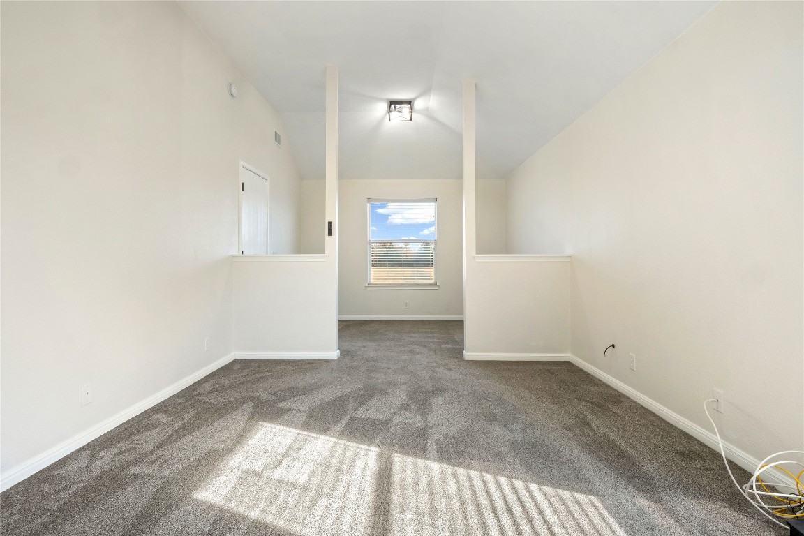 167 Hay Meadow Road Cedar Creek, TX 78612 - Photo 17 of 39 Primary bedroom featuring vaulted ceiling and dark carpet