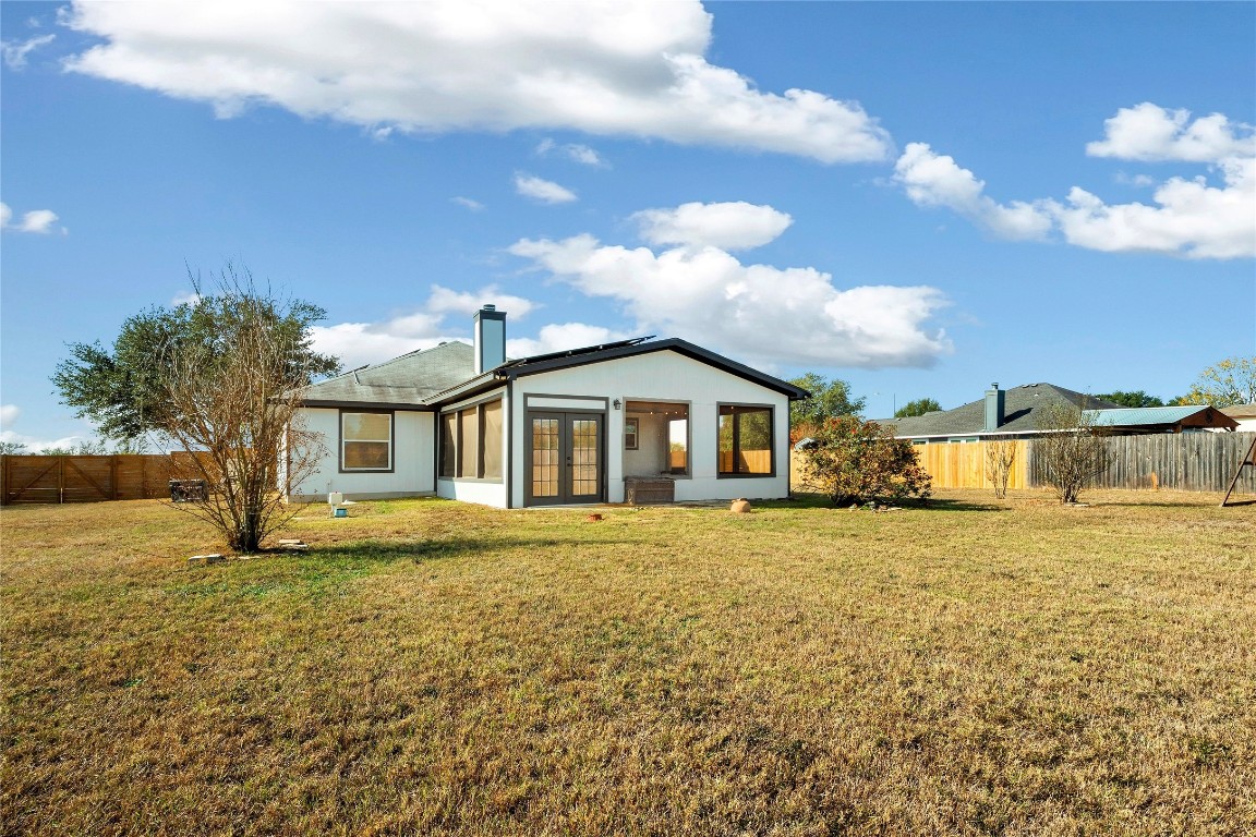 167 Hay Meadow Road Cedar Creek, TX 78612 - Photo 27 of 39 Rear view of structure with a fenced backyard, french doors, and a chimney