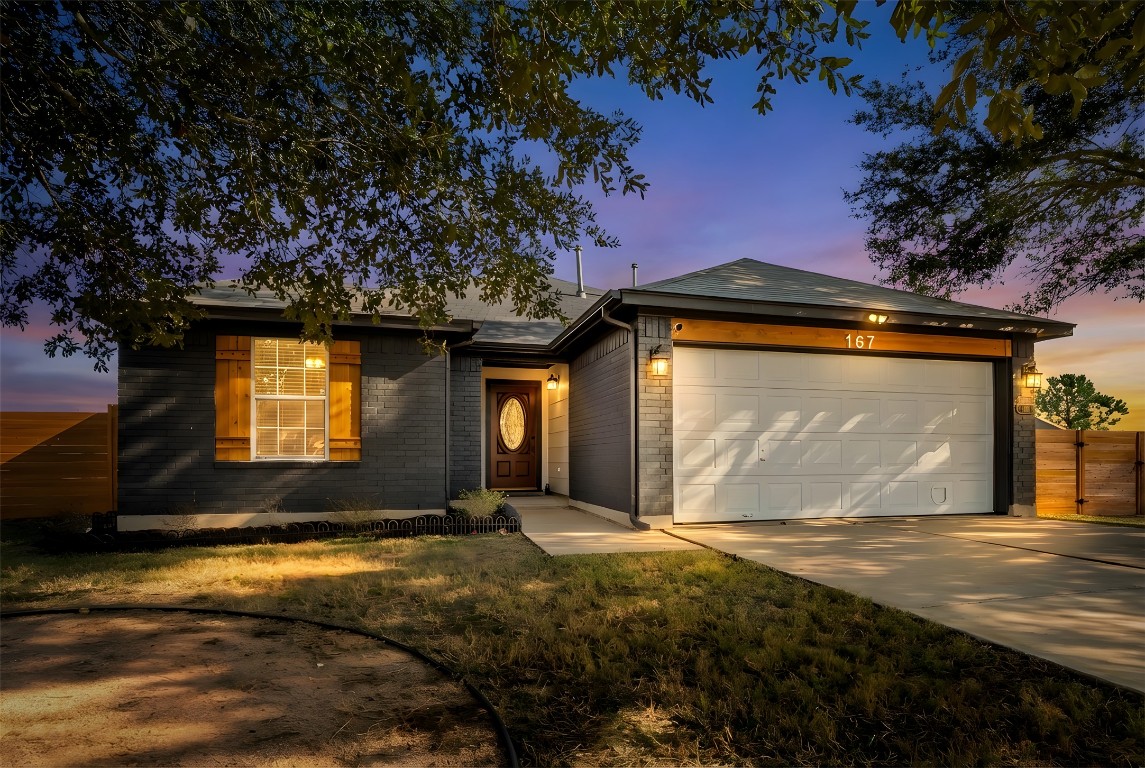 167 Hay Meadow Road Cedar Creek, TX 78612 - Photo 33 of 39 View of front of structure at dusk with brick siding, an attached garage, and concrete driveway