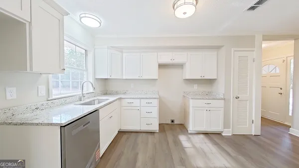 a kitchen with white cabinets appliances and sink