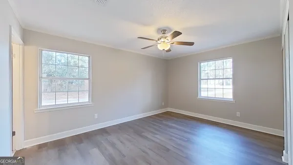 a view of an empty room with a window and wooden floor