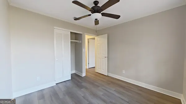 an empty room with wooden floor and a ceiling fan