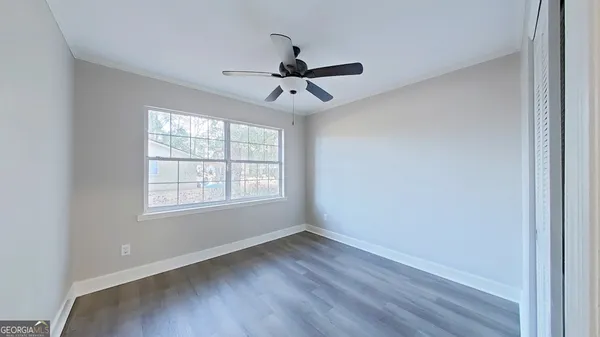 a view of an empty room with wooden floor and a window