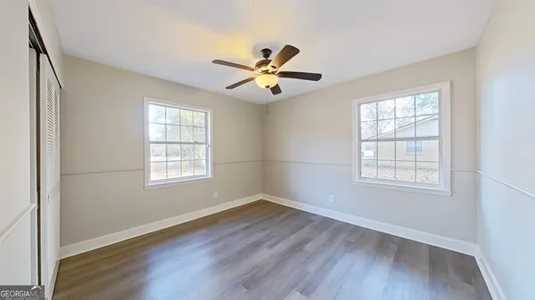 a view of an empty room with wooden floor and a window