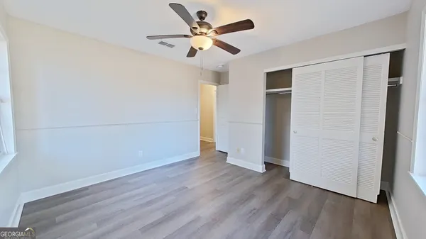 an empty room with wooden floor and a ceiling fan
