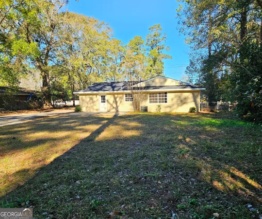 a view of a house with a big yard and large trees