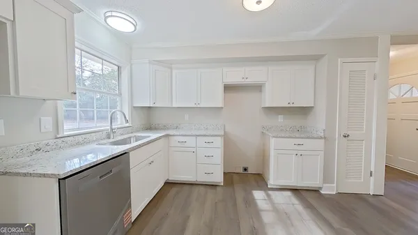 a kitchen with white cabinets appliances a sink and a window