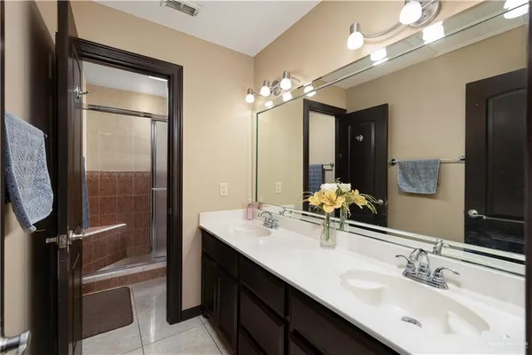 a bathroom with a double vanity sink a mirror and a shower