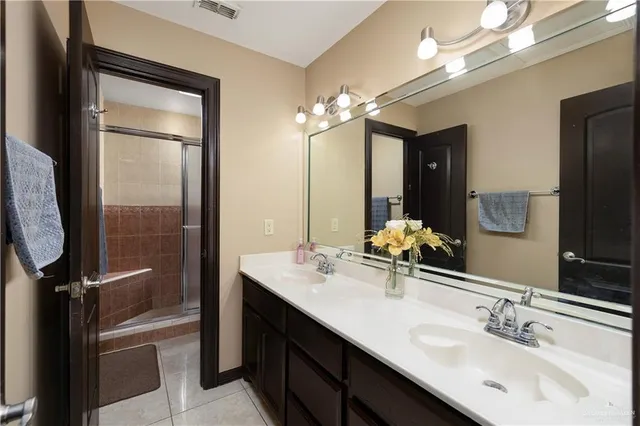 a bathroom with a double vanity sink a mirror and a shower