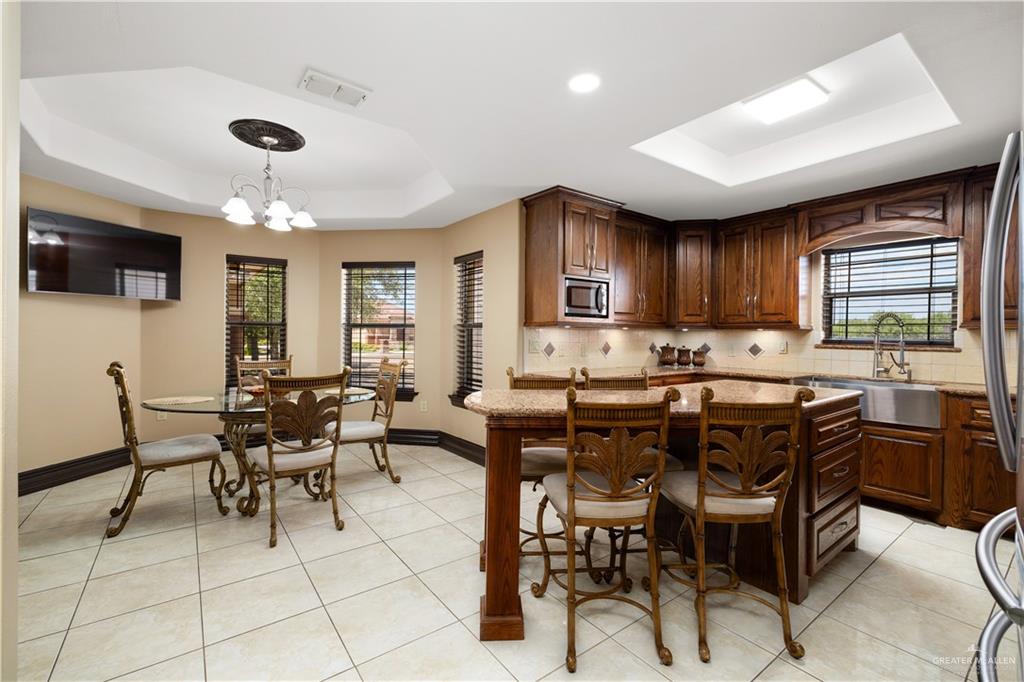 1257 Riverside Street Rio Grande City, TX 78582 - Photo 8 of 28 a kitchen with stainless steel appliances granite countertop a stove a sink dishwasher a dining table and chairs with wooden floor