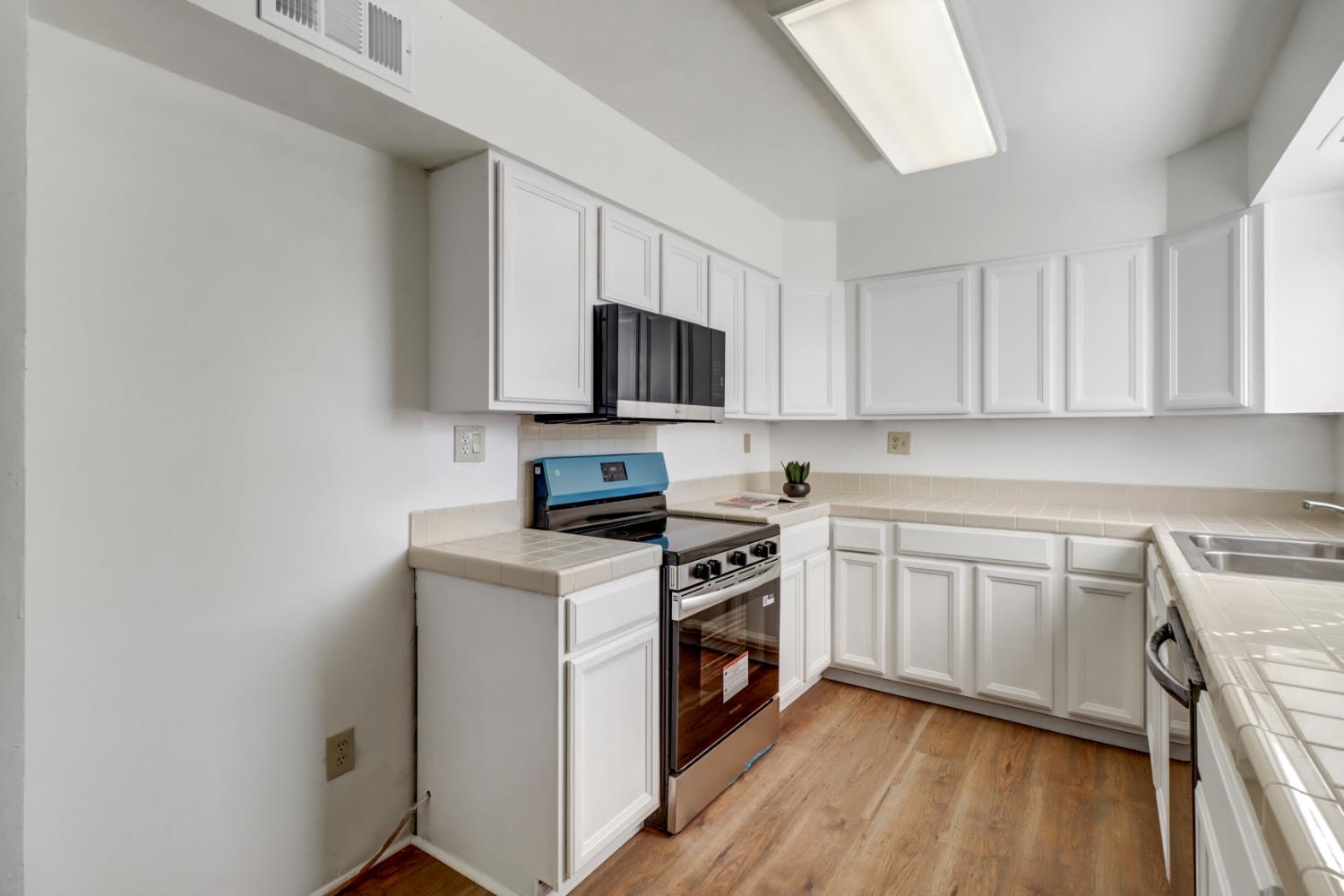 10556 Olson Drive Rancho Cordova, CA 95670 - Photo 14 of 46 a kitchen with a stove top oven and white cabinets