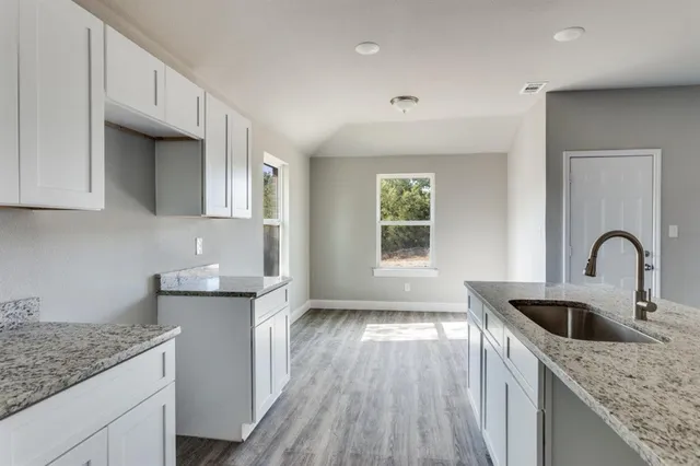 a kitchen with granite countertop white cabinets and sink