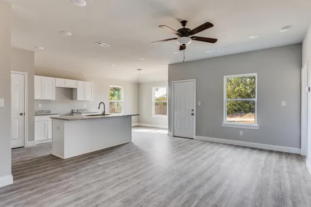a kitchen with a sink granite countertop cabinets wooden floor and a window