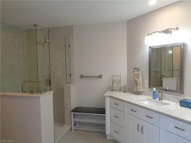 a bathroom with a shower sink vanity and mirror