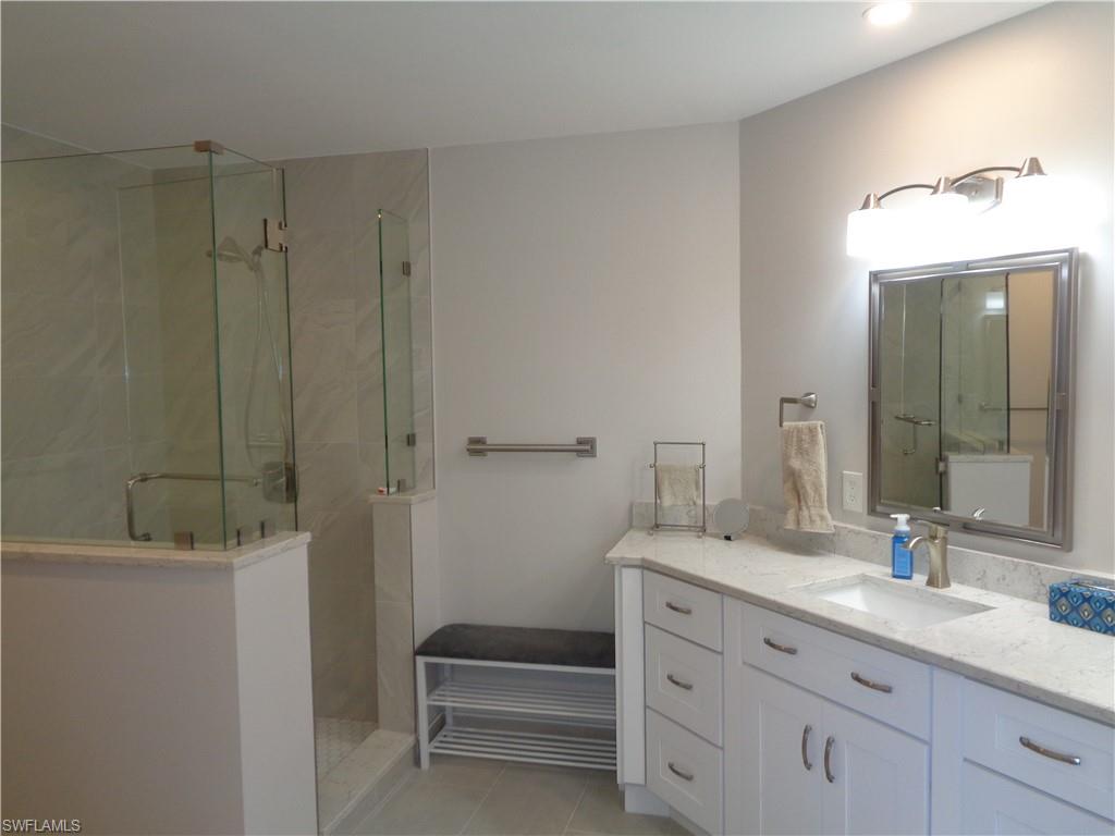 6250 Bellerive Avenue, Unit 5 Naples, FL 34119 - Photo 21 of 37 a bathroom with a shower sink vanity and mirror