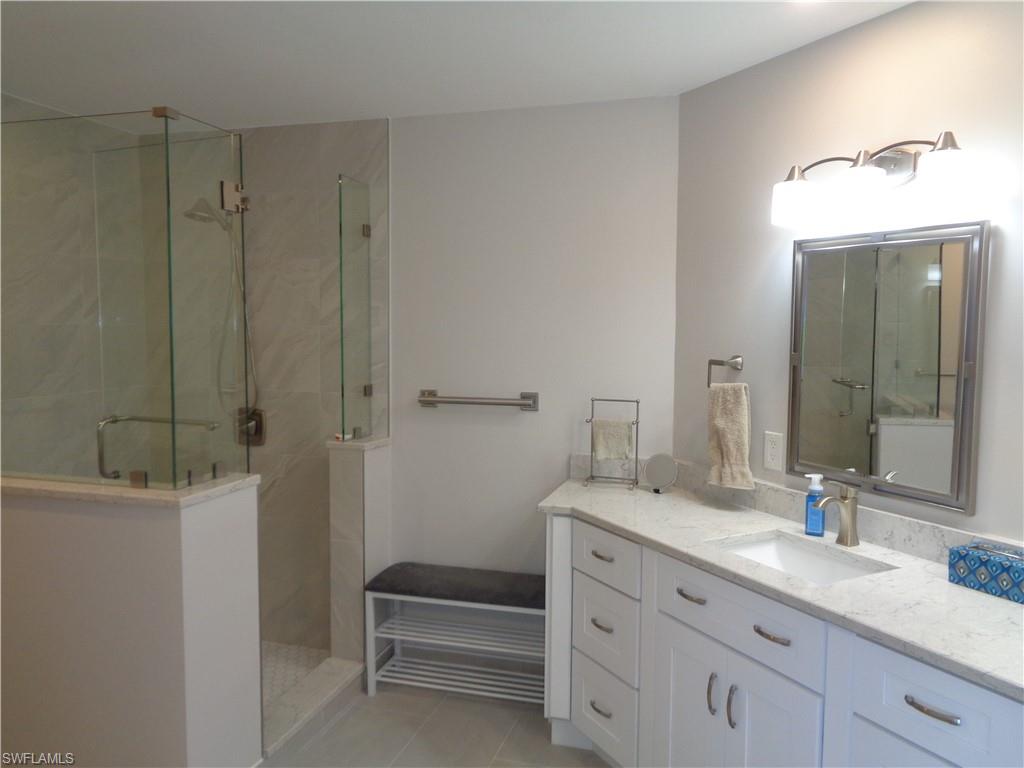6250 Bellerive Avenue, Unit 5 Naples, FL 34119 - Photo 22 of 37 a bathroom with a granite countertop sink a toilet and a mirror