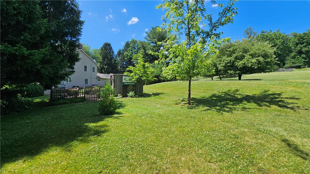 585 Buttermilk Road Hellertown, PA 18055 - Photo 50 of 82 Generous green lawns surround a comfortable residence, featuring a charming wooden fence and mature shade trees.
