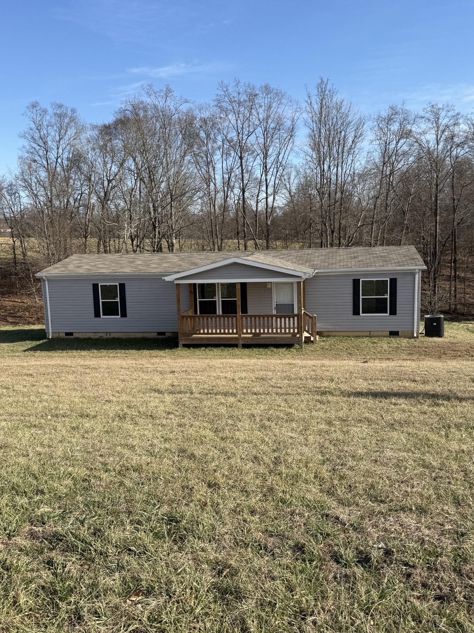 a front view of house with yard and trees in the background