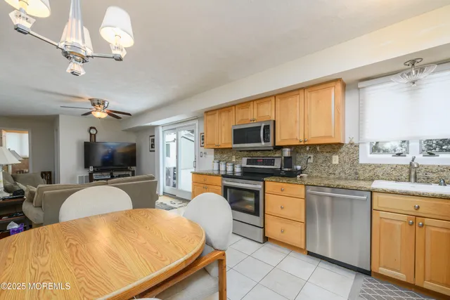 a large kitchen with kitchen island granite countertop a stove top oven a sink a counter space and dining table