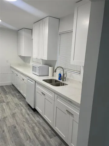a kitchen with white cabinets and sink