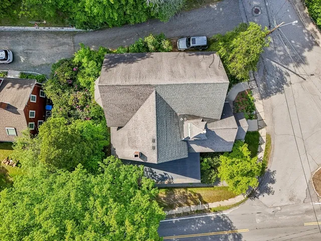 an aerial view of a house with a yard and a large tree