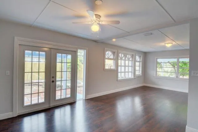 a view of an empty room with wooden floor and a window