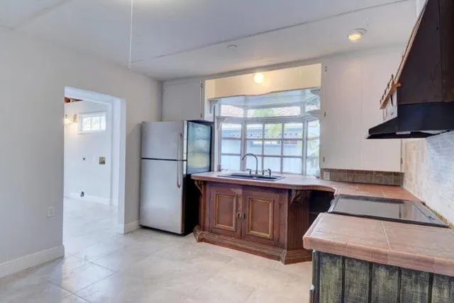 a kitchen with stainless steel appliances granite countertop a refrigerator a sink dishwasher a stove and a dining table with wooden floor