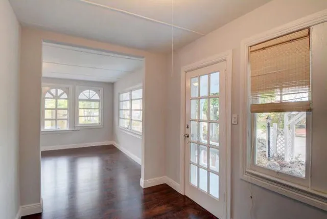 a view of an empty room with wooden floor and a window