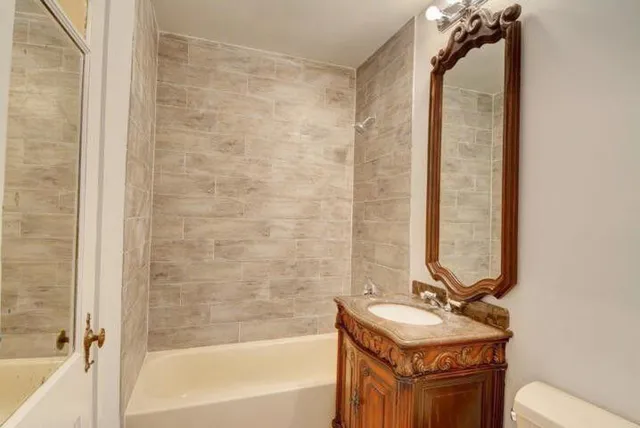 a bathroom with a tub sink and mirror