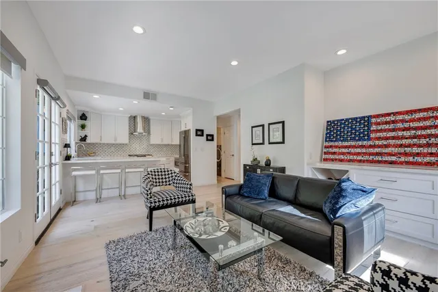 a large kitchen with granite countertop a stove a sink a refrigerator and white cabinets with wooden floor