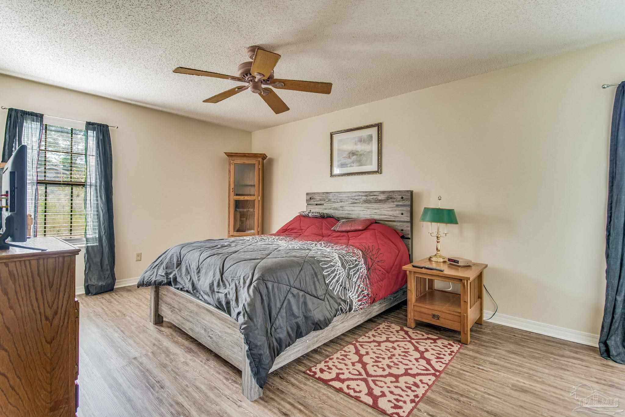 6201 Meadows Road Walnut Hill, FL 32568 - Photo 38 of 50 a bedroom with a bed and wooden floor
